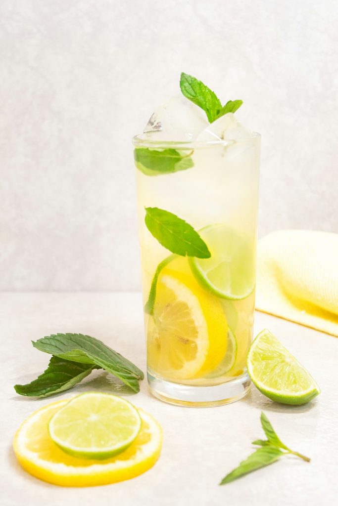 Refreshing lemon and mint infused homemade remedy drink with ice, citrus slices, and fresh herbs. Perfect for natural health and wellness, boosting immunity and hydration.