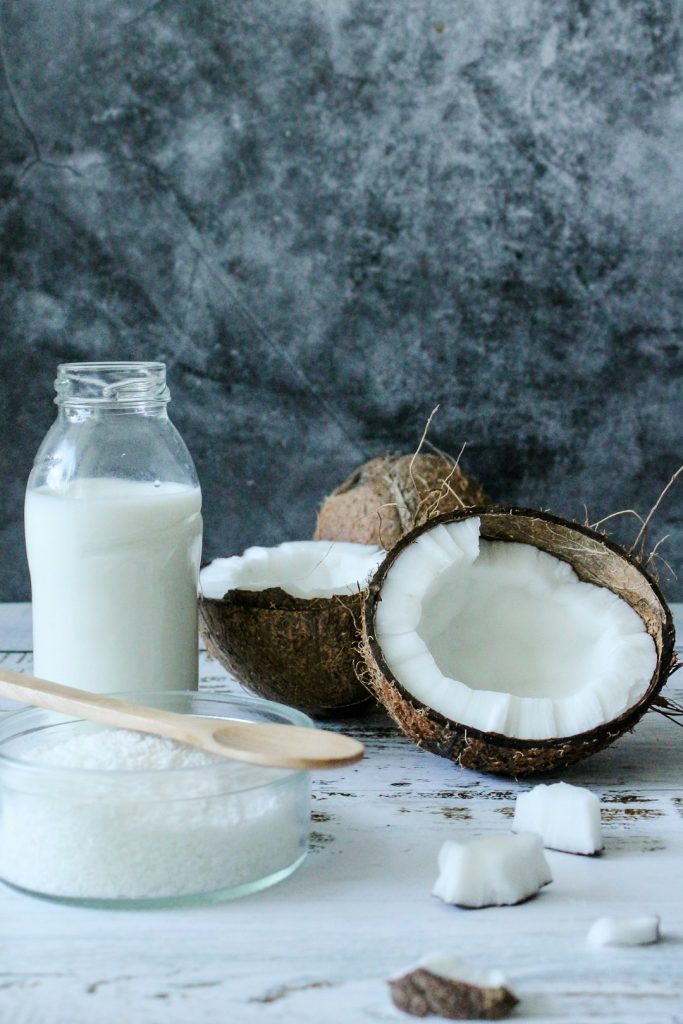 Fresh coconut with coconut milk and shredded coconut on rustic wooden background, showcasing natural remedies, healthy eating, and coconut-based remedies for wellness.